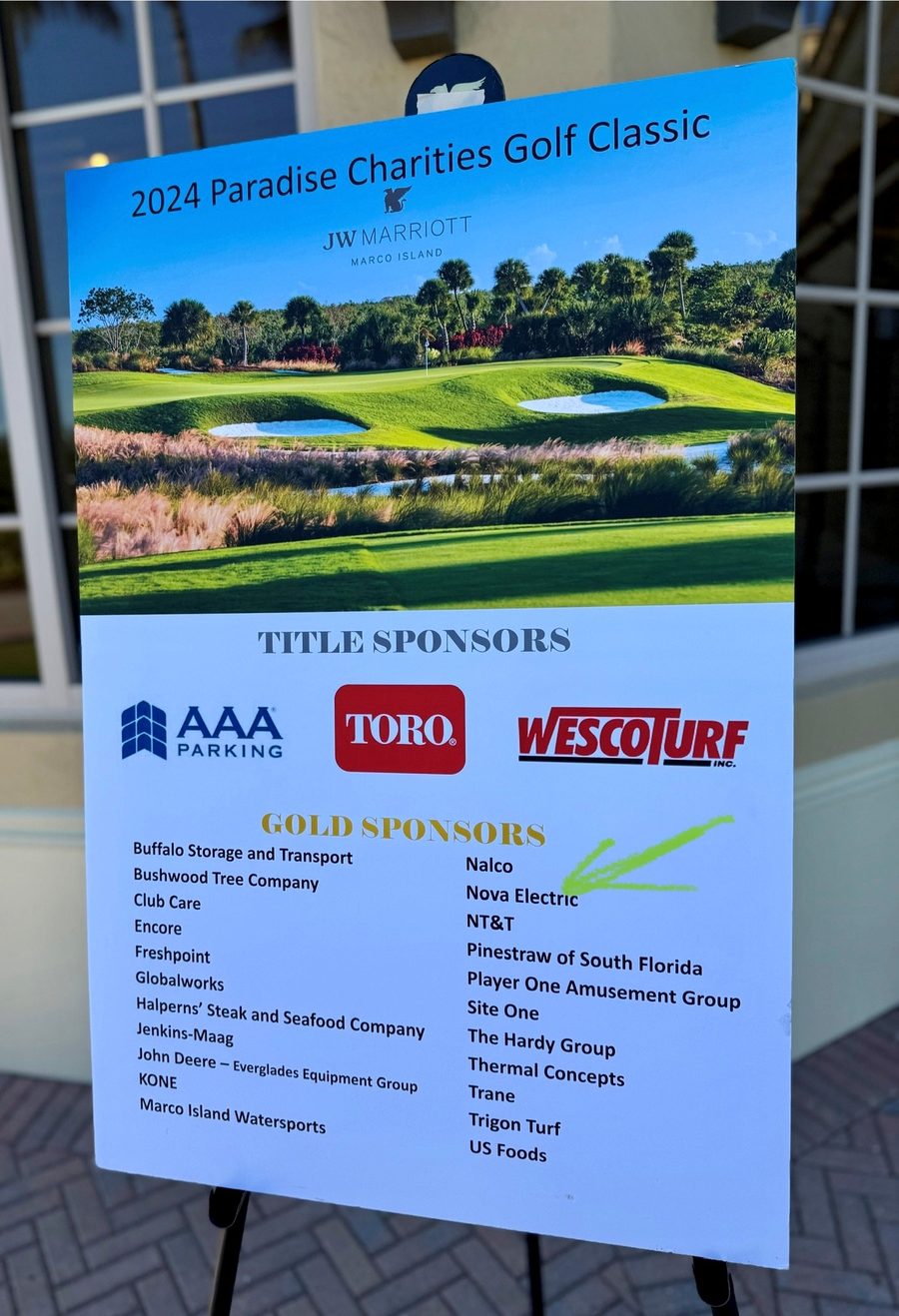 The 2024 Paradise Charities Golf Classic sponsor board on Marco Island listing Nova Electrical as a gold sponsor